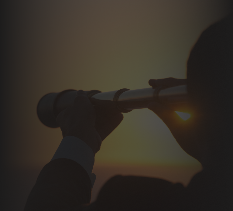 Silhouette of a person holding a telescope and looking towards the horizon during a sunset, symbolizing exploration and vision.