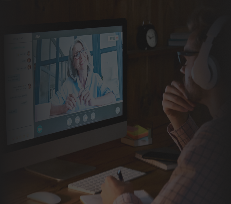 A communication coaching session taking place via video call, showing a participant wearing headphones and taking notes while attentively listening to the coach on the screen. The coach appears engaged and expressive, creating a collaborative and focused learning environment. The setting suggests a professional and dedicated approach to improving communication skills